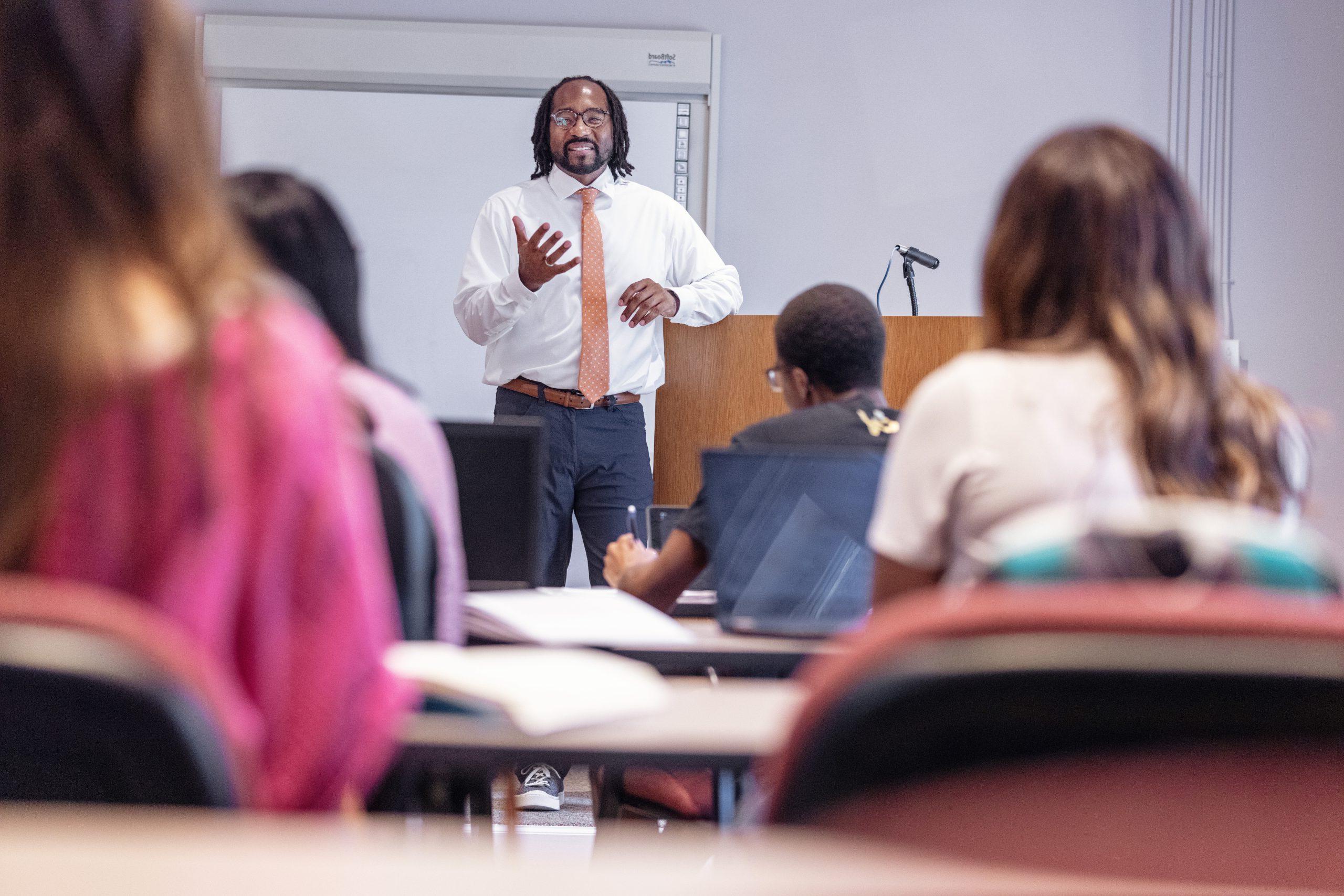 A 澳门在线赌城娱乐 professor smiles during a lecture inside a classroom in Wills Hall.